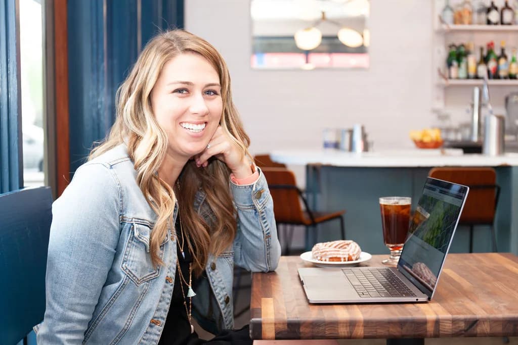 Molly Yardley smiling at a café table with a laptop